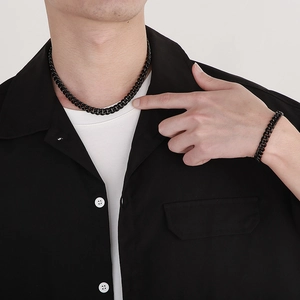 Dettaglio di un modello che indossa una collana a catena cubana nera e bracciale coordinato