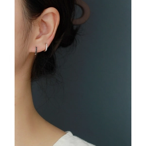Close-up of model wearing 925 silver hoop earrings with black and white crystal studs