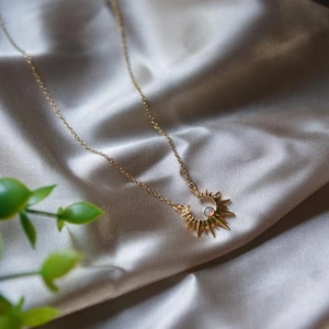 Golden sun necklace with opal pendant on silk fabric with elegant nature lighting