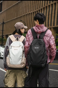 Outdoor street view of male and female models carrying black and beige hiking backpacks