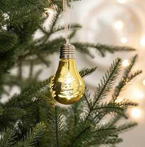 Close-up of golden LED bulb ornament with Christmas tree pattern hanging on a branch