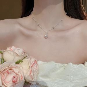 Detailed view of irregular pearl pendant necklace on neck with floral background