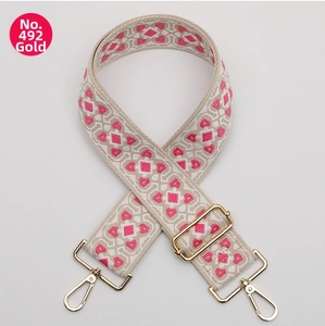 Close-up of pink geometric diamond embroidery on ethnic style wide woven bag strap with gold hooks