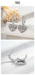 Detail of silver heart huggie earrings with cubic zirconia and floral hollow pattern