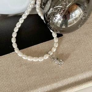 Detailed view of elegant pearl bracelet featuring a minimalist silver bear charm pendant