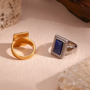 Close-up of gold and silver seal rings with blue gemstone on natural stone background