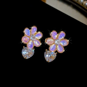 Macro shot of resin flower earrings with purple pink petals and heart-shaped zircon drop