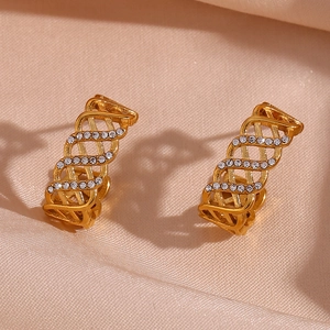 Détails macro des boucles d'oreilles dorées en C avec motif ajouré et zircons