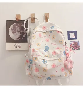 Detail of white floral canvas backpack with cute pink plush flower charm and cartoon prints