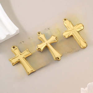 Macro detail of three polished gold titanium steel cross pendants for DIY necklaces