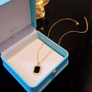 Macro shot of gold rectangle pendant with black inlay and zircons in a gift box