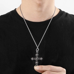 Detailed view of silver cross pendant with blue turquoise inlay on twisted chain worn by model