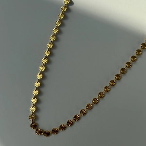 Detail of 18k gold plated waist chain with sunburst texture metal discs on white background