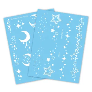 Luminous temporary butterfly tattoos featuring stars and moon designs in white ink on blue paper