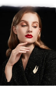 Detailed close-up of an elegant wing brooch with white zircons on a black blazer