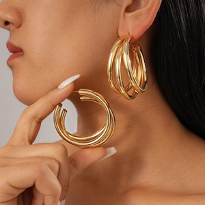 Detail shot of golden multi-layered geometric round earrings on model for a bold style