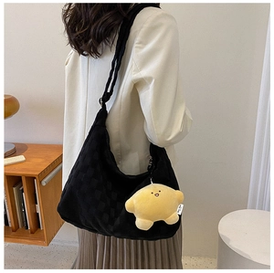 Detail of checkered tote bag with a yellow star plush charm shown on a female model