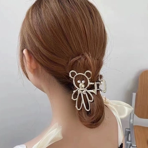 Silver metal bear hair claw clip with pearl accents worn on brown hair from behind
