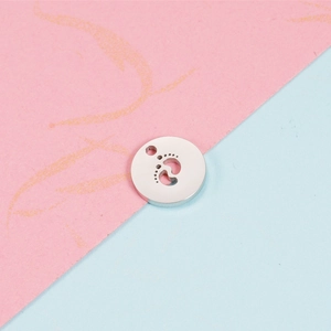 Macro detail of silver mirror stainless steel round pendant with hollow baby footprint