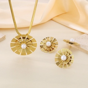 Détail du pendentif fleur dorée et des boucles d'oreilles perles sur fond en soie