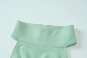Close-up of light green knitted fabric showing halter neckline and stitching details