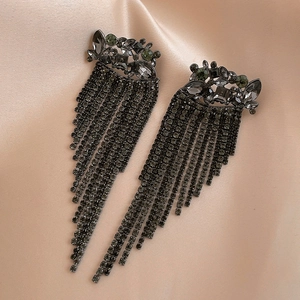 Macro shot of gun-black tassel earrings with dark grey rhinestones on champagne satin