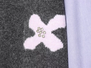 Primer plano de punto gris oscuro con bordado floral morado y detalles de pedrería