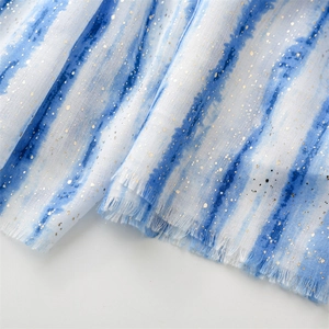 Detail of blue and white tie-dye scarf featuring gold foil spots and fringe edges