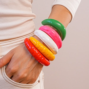 Dettaglio di cinque braccialetti in acrilico colorati con trama a spirale e finitura lucida