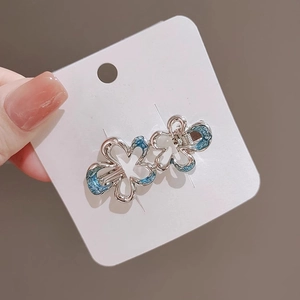 Detail of silver flower hair clips with blue enamel petals on a display card