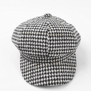 Detail of houndstooth newsboy cap featuring black and white tweed with subtle gold threads
