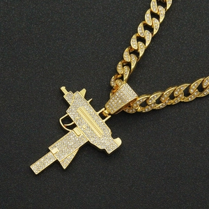 Macro detail of gold Cuban chain and gun pendant fully encrusted with clear rhinestones