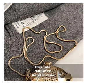 Close-up of golden fish pendant with scale texture on a sleek snake chain necklace