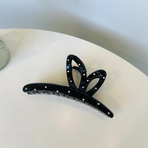 Detailed view of a black hair claw clip with white polka dots in a bow design