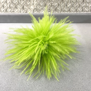 Close-up of bright green ostrich feather brooch with soft fluffy texture for party wear