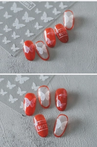 Détails macro d'autocollants 5D papillon blanc sur vernis à ongles rouge gelée