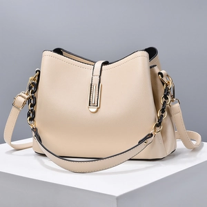 Minimalist beige shell crossbody bag with litchi texture and gold buckle on stand