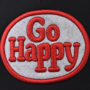 Gros plan sur l'écusson brodé Go Happy d'une casquette de baseball noire délavée