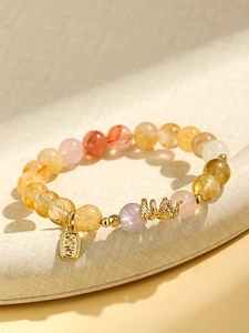 Detail of beaded crystal bracelet with golden snake charm and fortune pendant