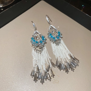 Macro detail of silver flower earrings with sky blue crystals and smoky grey tassels