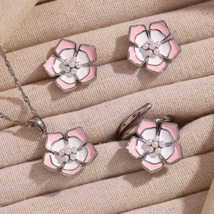 Detailed set of floral jewelry with pink petals and small pearls in a beige gift box