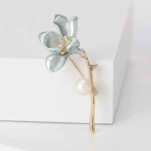 Detail of light blue flower brooch with golden stem and elegant white pearl accent