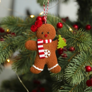 Plush gingerbread man Christmas tree ornament with scarf and tree on a pine branch