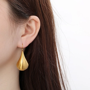 Close-up of elegant hollow teardrop hook earring in gold finish on a model's ear