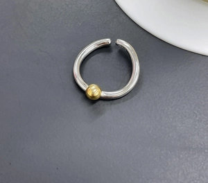 Close-up of S925 sterling silver ring featuring a minimalist golden bead accent