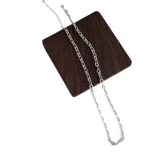 Minimalist silver chain necklace with geometric oval links on a wooden display block
