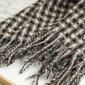 Detailed close-up of soft plaid scarf fabric with woven tassels in black and brown