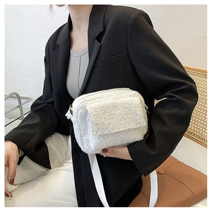 Detailed close-up of a white faux fur crossbody bag featuring a soft plush texture strap