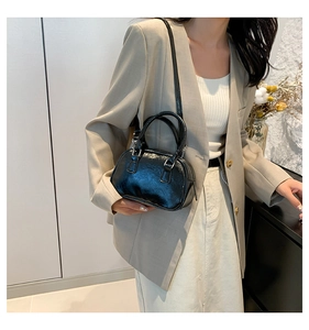 Detailed view of black patent leather bowling bag worn on shoulder by model