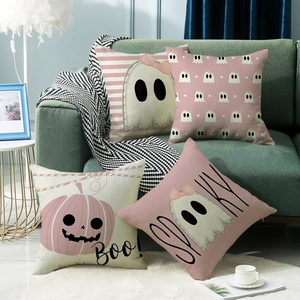 Set of four pink Halloween throw pillow covers with ghosts and Boo lettering on a sofa